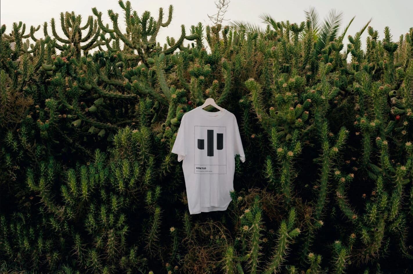 Kaktus Adventure t-shirt hung against a wall of cacti